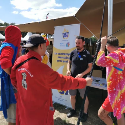 Stand Testi Cho Jour J au Village du V and B Fest' dans l'Espace Solidaire : sensibilisation de festivaliers par Antoine (de face)