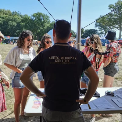 Stand Testi Cho Jour J au Village du V and B Fest' dans l'Espace Solidaire : sensibilisation de festivaliers par Antoine (de dos)